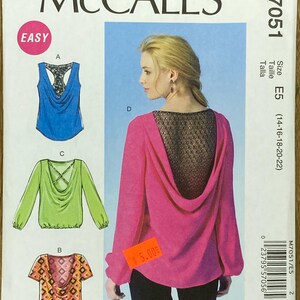 May include: McCall's sewing pattern M7051, featuring designs for tops with cowl necklines and various sleeve lengths. The pattern includes a pink top with a lace back detail. The size is E5, fitting sizes 14-22.