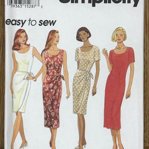 Peut inclure: Patron de couture Simplicity avec quatre modèles de robes. Le patron comprend les tailles 6, 8 et 10, et est étiqueté "easy to sew". Les robes comprennent une robe portefeuille blanche, une robe portefeuille rouge à fleurs, une robe portefeuille beige à pois et une robe fourreau rouge.