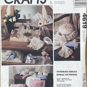 May include: A vintage McCall's Crafts pattern envelope featuring a collage of Victorian-era craft projects. The image showcases delicate lace items, including purses, pillows, and decorative accessories. The text reads "Victorian Fancies Details Victoriens."