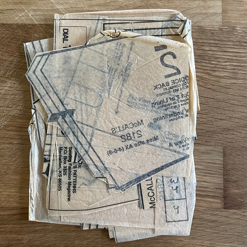 May include: A stack of McCall's sewing patterns, including pattern number 5185, for sizes 8-14. The patterns are printed on beige paper with black ink.
