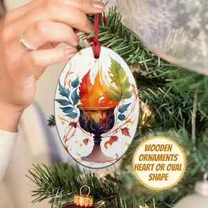 May include: Oval-shaped wooden Christmas ornament with a watercolor design of a chalice with flames and colorful leaves. The ornament is suspended by a red ribbon. Text on the image reads "WOODEN ORNAMENTS HEART OR OVAL SHAPE."
