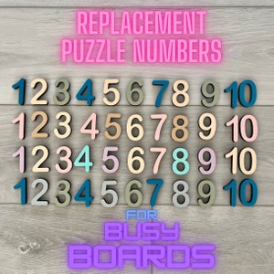 May include: Replacement puzzle numbers for busy boards. The numbers 1 through 10 are shown in four rows, each row with a different color scheme. The numbers are made of wood and have a painted finish. The colors include pink, blue, green, yellow, and brown.
