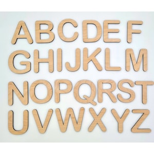 May include: A set of 26 wooden letters, each letter is cut out of a light brown wood and has a dark brown outline. The letters are arranged in alphabetical order, starting with A and ending with Z.
