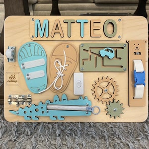 Educational Montessori busy board for toddlers with personalized puzzle name, shoe Velcro, shoe with lace, maze, zipper training, fun wheels, buckle opening and closing exercise, lock, switch and fun wheel. This busy board will keep your child busy.