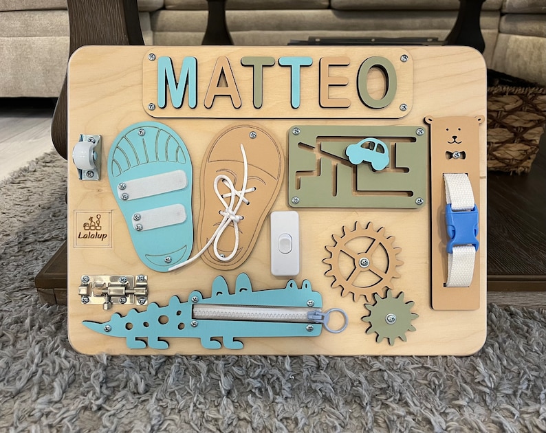 Educational Montessori busy board for toddlers with personalized puzzle name, shoe Velcro, shoe with lace, maze, zipper training, fun wheels, buckle opening and closing exercise, lock, switch and fun wheel. This busy board will keep your child busy.