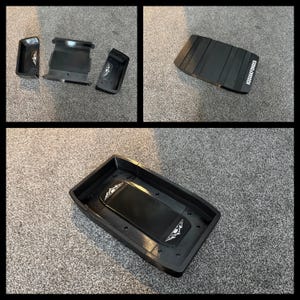 May include: Black plastic automotive parts, including a rectangular tray and several smaller components. The tray has a raised central section and a logo. The text "KODIAK FORGED" is visible on one of the parts.