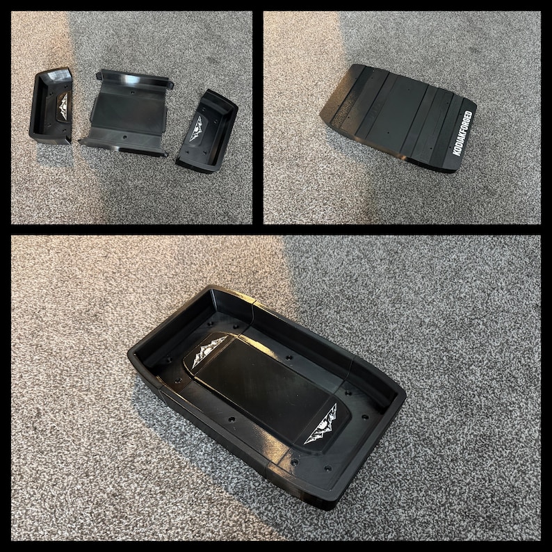 May include: Black plastic automotive parts, including a rectangular tray and several smaller components. The tray has a raised central section and a logo. The text "KODIAK FORGED" is visible on one of the parts.