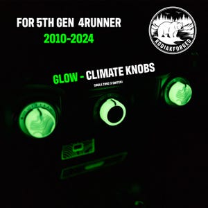 May include: Black dashboard with glowing green climate control knobs. The knobs are labeled "GLOW - CLIMATE KNOBS" and "SINGLE ZONE (3 SWITCH)". The text "FOR 5TH GEN 4RUNNER 2010-2024" is also visible. A logo with a bear is in the upper right corner.