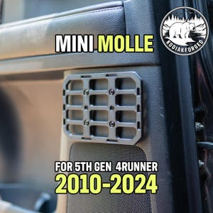 Op de afbeelding: Een grijze Mini Molle-paneel voor een 5th Gen 4Runner (2010-2024) geïnstalleerd op een autodeur. Het paneel heeft een rasterontwerp en is bevestigd met schroeven. De tekst "Kodiak Forged" staat in een cirkelvormig logo.