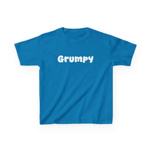 May include: A bright blue short-sleeved t-shirt featuring the word Grumpy printed in a bold, white, rounded sans-serif font across the center of the chest. The garment has a classic crew neckline and a standard straight-cut hem.
