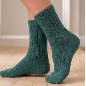 Puede incluir: Un par de calcetines de color verde azulado oscuro hasta la media pantorrilla con un patrón de punto acanalado vertical. Los calcetines cuentan con una sección reforzada en el talón y la puntera, con una textura desde el puño al pie.