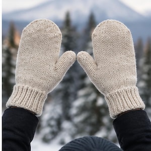 Peut inclure: Une paire de moufles en tricot beige avec une construction en fil épais texturé et des poignets côtelés. Les moufles présentent une section de pouce arrondie et un design simple de couleur unie, couvrant entièrement les mains et les doigts.