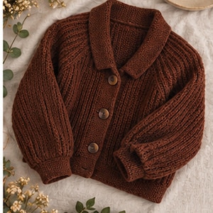 May include: A dark brown knit cardigan featuring a folded collar, long sleeves with ribbed cuffs, and three round buttons down the front. The garment is constructed with a vertical ribbed texture throughout the body and sleeves.