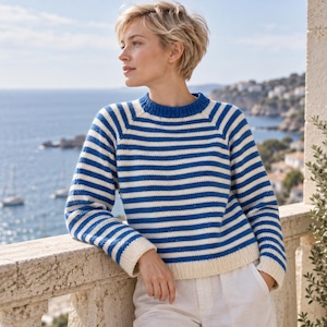 May include: A long-sleeved knit sweater featuring a horizontal striped pattern in royal blue and off-white. The garment has a ribbed crew neckline, ribbed cuffs, and a ribbed hem, constructed with a classic raglan sleeve design for a structured fit.