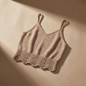 Peut inclure: Un débardeur en tricot beige doté d'un col en V, de fines bretelles et d'un ourlet festonné décoratif avec un motif chevron texturé. Le vêtement est confectionné dans un fil de couleur unie avec un point de tricot uniforme sur tout le corps.