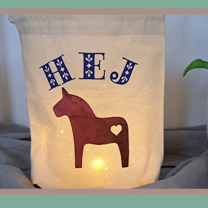 Scandinavian decoration. Dala horse with the inscription HEJ. A sustainable lantern without an open flame. Light bag in Swedish style. Hygge.