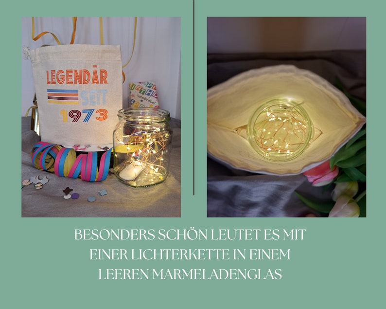 May include: A white canvas bag with the text "LEGEND&Auml;R SEIT 1973" printed on it. A clear glass jar with a string of fairy lights inside is sitting on a table next to the bag. The jar is surrounded by confetti and a colorful streamer.