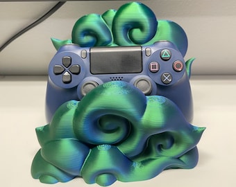Może przedstawiać: Stojak na kontroler wydrukowany w 3D w kształcie zielono-niebieskiej chmury. Stojak jest zaprojektowany do trzymania kontrolera Playstation 4.