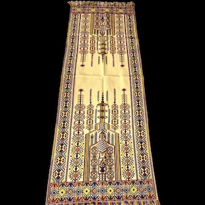 May include: A rectangular prayer rug featuring a cream-coloured base with intricate geometric embroidery in red, blue, yellow, and green. The design includes a central mihrab arch motif, decorative borders, and fringed edges on both ends.