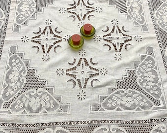 May include: White crocheted tablecloth with intricate lace detailing and three small tealight candles in glass holders.