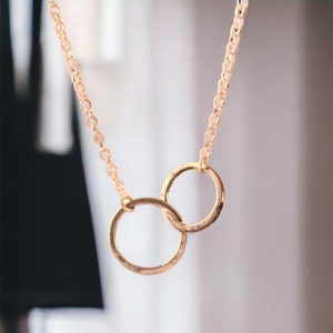 A minimalist sterling silver necklace with two connected circles. This is a unity necklace.