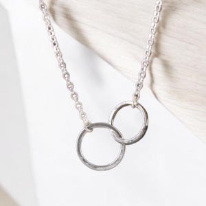 A minimalist sterling silver necklace with two connected circles. This is a unity necklace.