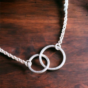 A minimalist sterling silver necklace with two connected circles. This is a unity necklace.