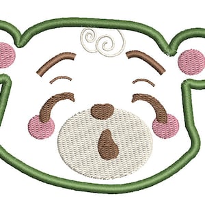 Könnte beinhalten: Grünes umrandetes Bären Gesicht mit braunen Augen, einer braunen Nase und rosa Wangen. Der Bär hat eine weiße, flauschige Schnauze und einen weißen Wirbel auf dem Kopf.