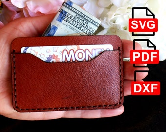 May include: A brown leather card holder with a stitched edge, featuring a pocket for cash or cards. The holder is being held in a hand, with a dollar bill and a card with the word "MONEY" visible inside.