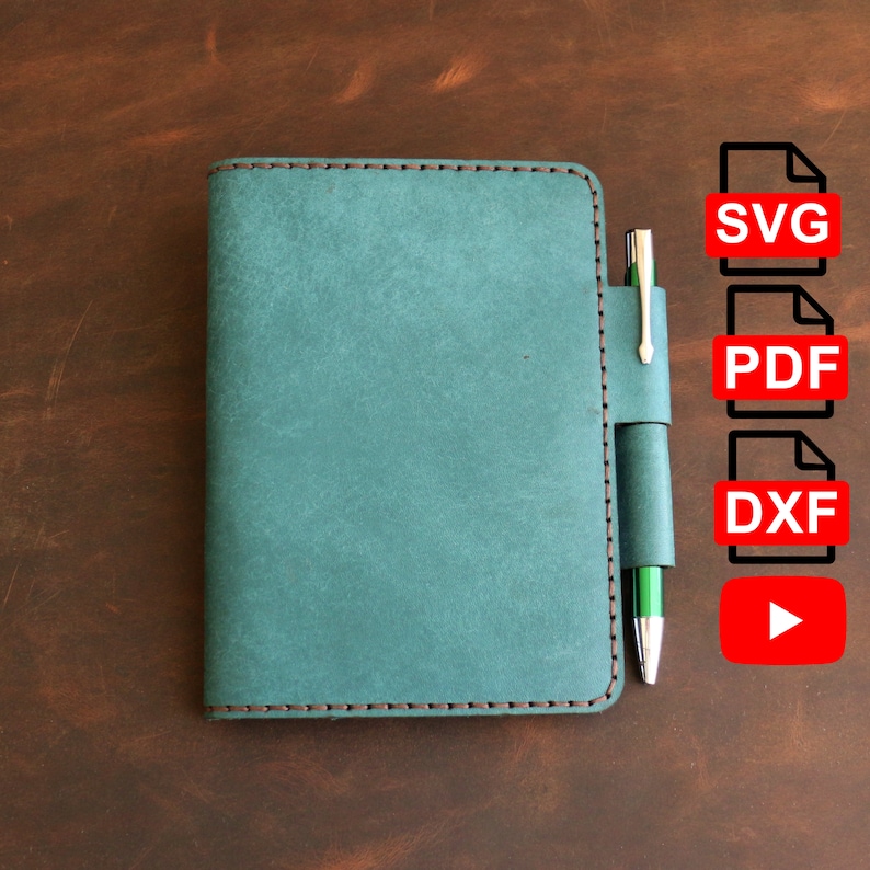 Op de afbeelding: Een teal lederen notitieboekomslag met een pennenhouder en bruine stiksels. De omslag ligt op een bruin houten oppervlak. De afbeelding bevat de tekst "SVG", "PDF", "DXF" en een afspeelknop.