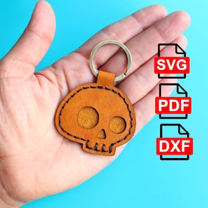 May include: A brown leather skull keychain with a stitched edge. The keychain is attached to a silver key ring. The image also shows the words "SVG", "PDF", and "DXF" in red text.