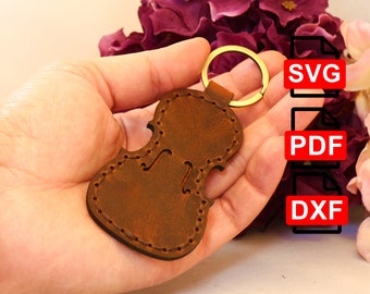 May include: Brown leather violin keychain with a gold key ring.  The keychain is in a hand, and the image includes the text "SVG", "PDF", and "DXF".
