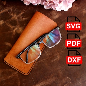 May include: A brown leather glasses case with a pair of glasses inside. The case has a stitched edge. The image also includes a graphic of three file icons with the text "SVG", "PDF", and "DXF" in red.