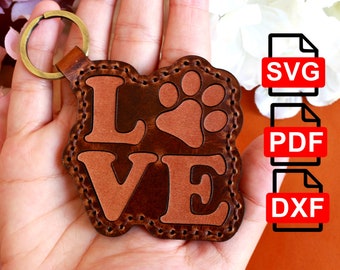 May include: Brown leather keychain with the word "LOVE" and a paw print in the centre. The keychain is attached to a gold key ring.
