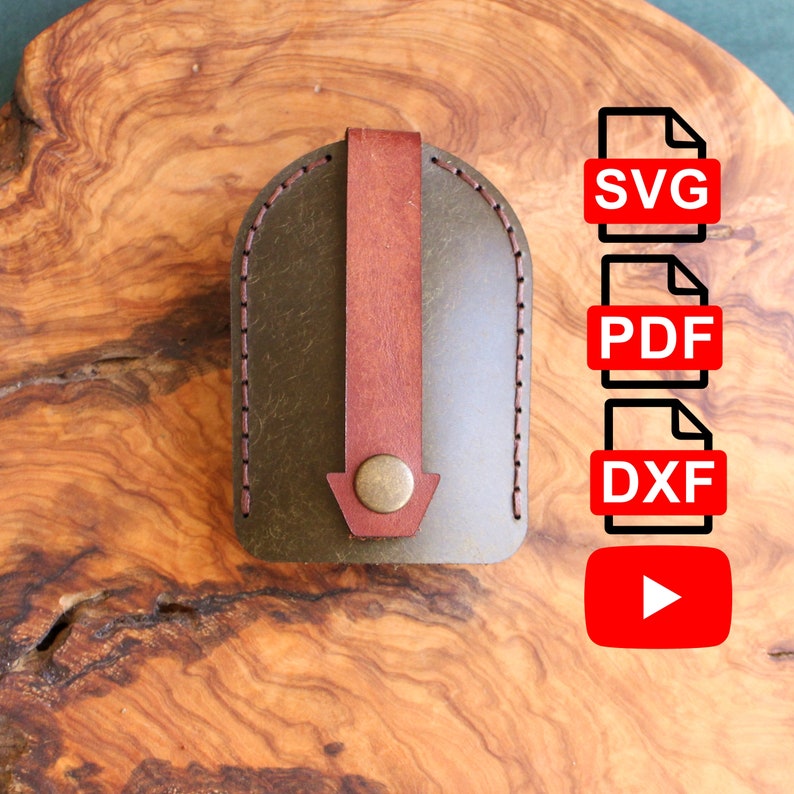 May include: A brown leather key fob with a brown strap and a metal button. The fob is on a wooden surface. The image also includes text for SVG, PDF, DXF, and a play button.