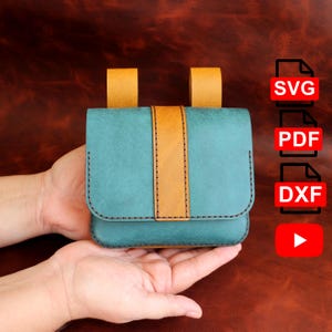 May include: A teal leather pouch with a tan vertical stripe and two tan loops. The pouch is held in two hands. The image also includes the text "SVG", "PDF", and "DXF".