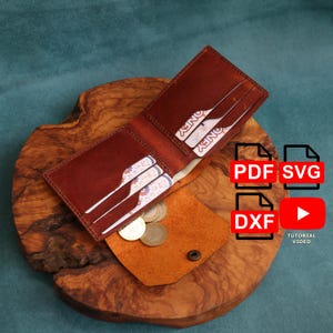 May include: Open brown leather wallet with multiple card slots and cash. A small, tan leather coin purse with a snap closure sits below the wallet. Several coins are visible. The wallet is on a wooden surface.