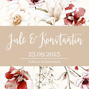 May include: A wedding invitation with a watercolor floral design in shades of white, red, and green. The text reads "Jule & Konstantin" and "23.09.2023 Schloss Lichtenstein".