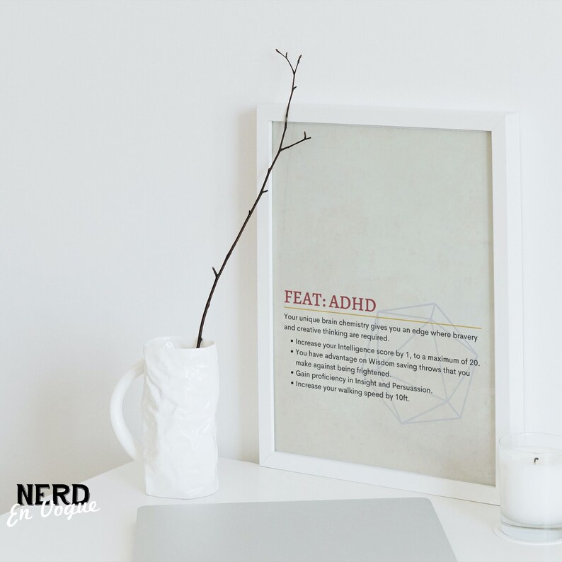 Puede incluir: Una impresi&oacute;n enmarcada en blanco con el texto "FEAT: ADHD" y una descripci&oacute;n de los beneficios de tener TDAH. La impresi&oacute;n est&aacute; sobre una superficie blanca con una taza blanca y una vela blanca.