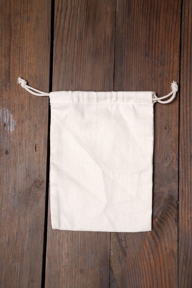 May include: A white cotton drawstring bag on a wooden background.