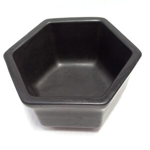 May include: A black hexagonal ceramic planter with a smooth, glossy finish. The planter is empty and ready for planting.