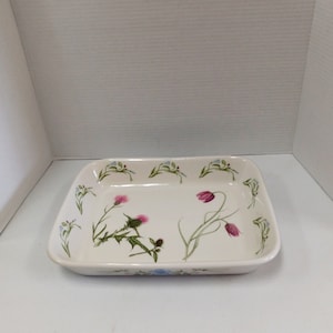 May include: White rectangular ceramic baking dish with a floral design featuring pink and green thistles and blue flowers around the rim.