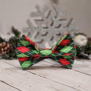May include: A green and red plaid bow tie with a diamond pattern. The bow tie is made of fabric and has a festive holiday look.