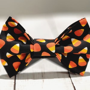 Puede incluir: Una pajarita negra con un patrón de maíz dulce naranja y amarillo.