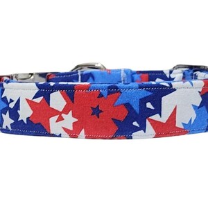May include: A dog collar with a pattern of red, white, and blue stars. The collar has a silver metal buckle. The design is suitable for a pet.