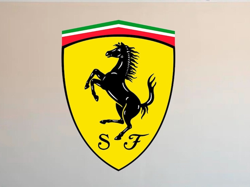 Puede incluir: Un emblema amarillo en forma de escudo con un caballo encabritado negro, el logotipo de Ferrari. La parte superior del escudo tiene rayas verdes, blancas y rojas. Las letras "SF" est&aacute;n en la parte inferior del escudo.