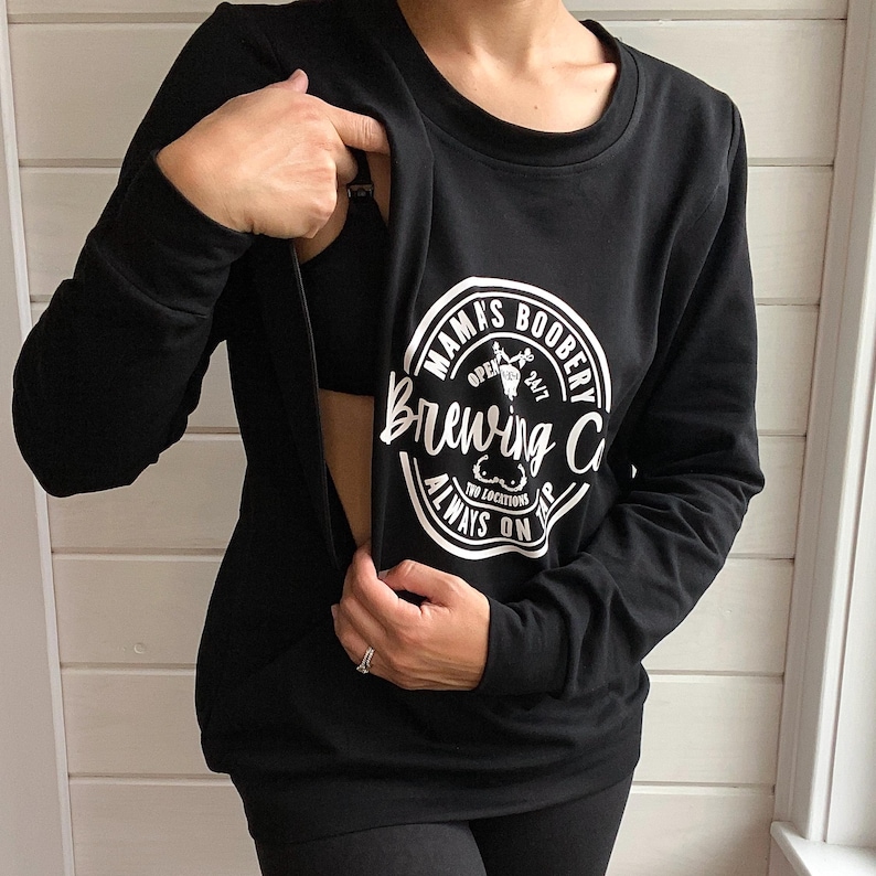 Beige Crewneck Sweatshirt with a logo in black Mama Boobery Brewing Co. Always on Tap 24/7 Two Locations. Breastfeeding Friendly Sweatshirt with zippers on either side that zip from the bottom up for easy accessibility to latch baby to nurse.