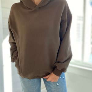 Pu&ograve; includere: Una felpa con cappuccio marrone oversize con coulisse. La felpa &egrave; realizzata in un tessuto morbido e confortevole e ha una vestibilit&agrave; rilassata.