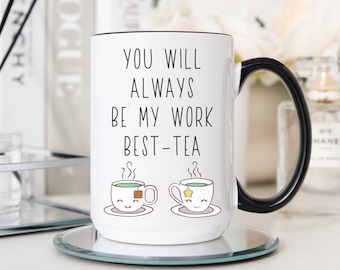 May include: White ceramic mug with a black handle. The mug has a black rim and the text "You will always be my work best-tea" with two cartoon teacups with steam coming from them.