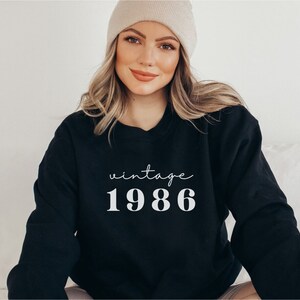 May include: Black sweatshirt with white text that reads "vintage 1986".